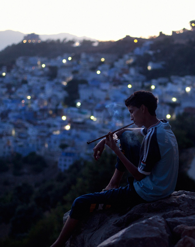 A young man smokes and relaxes during dusk, Chefchaouen, Morocco