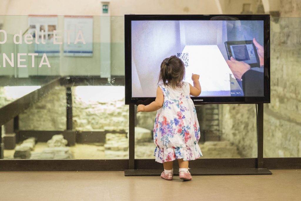 bambina guarda stupita i resti romani all'ingresso del museo del campanone;