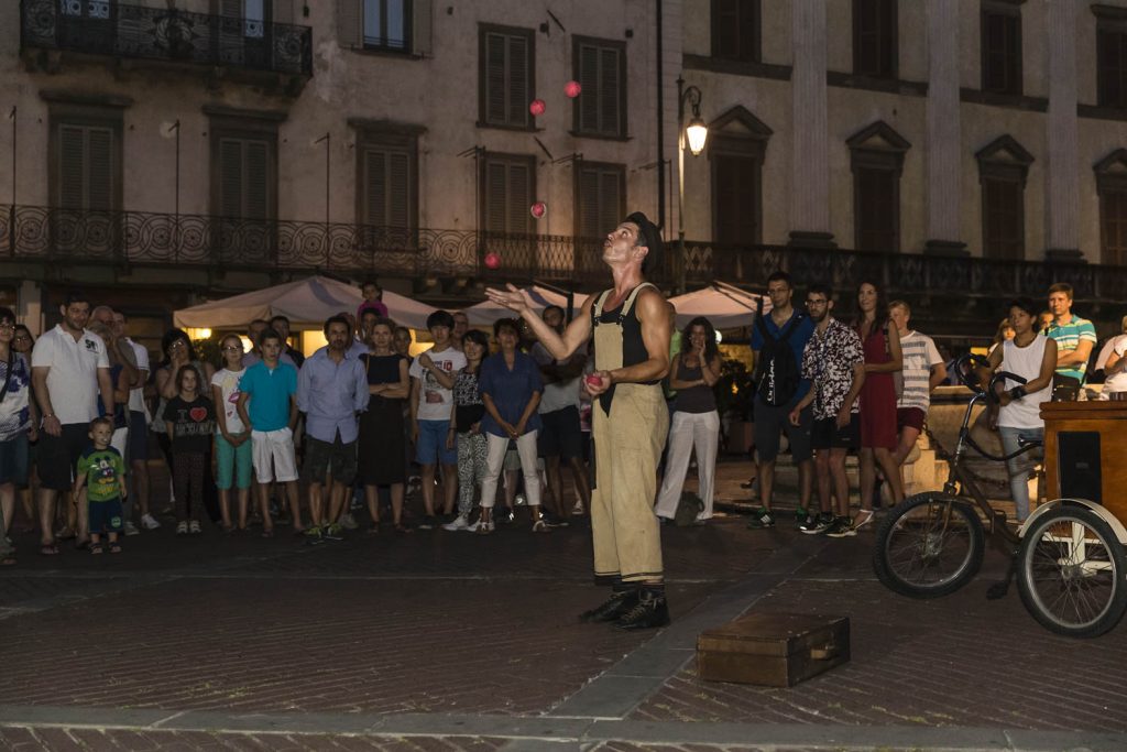 bambini stupiti davanti allo spettacolo di un giocoliere;