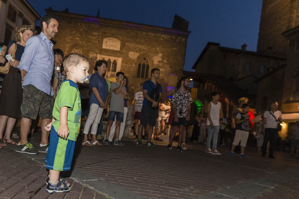 bambini stupiti davanti allo spettacolo di un giocoliere;