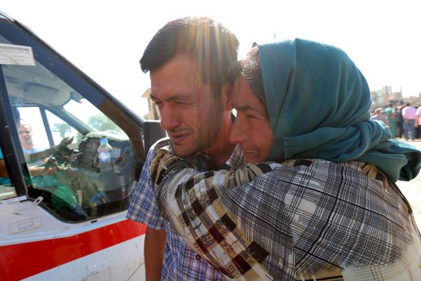 Abdullah Kurdi mourns with his relative during the funeral of his toddlers at the Syrian border town of Kobani