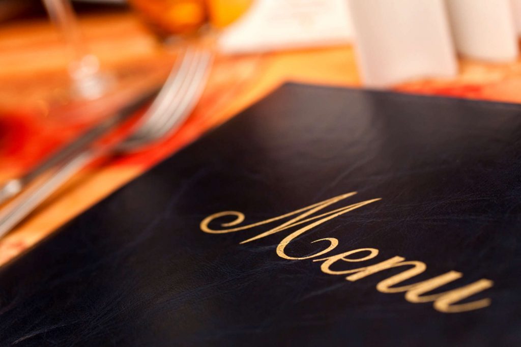 A menu and knife and fork cutlery laid on a restaurant table