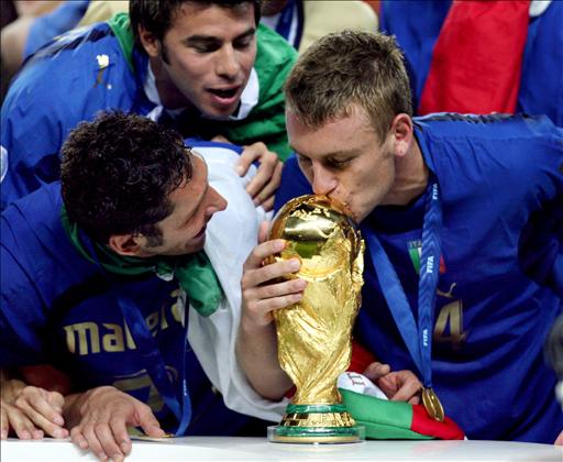 Italian defender Marco Materazzi (L) looks on as Italian midfielder Daniele De Rossi (R) kisses the World Cup trophy following their victory in the World Cup 2006 final football match between Italy and France at Berlin's Olympic Stadium, 09 July 2006. Italy won 5-4 in the penalty shootout after the teams finished in extra time 1-1. AFP PHOTO / ODD ANDERSEN