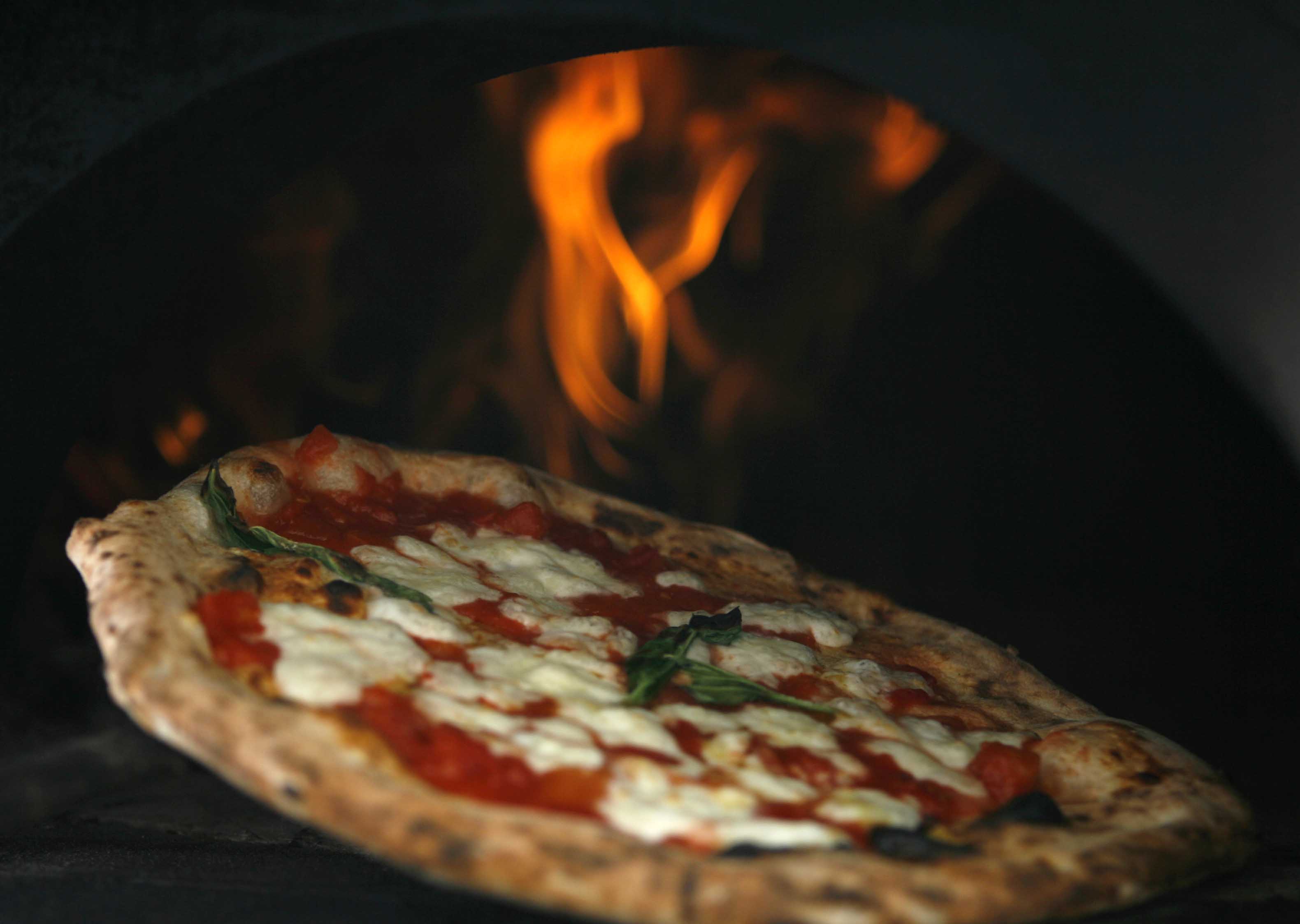 Pizza is removed from oven during a protest to demand stricter price controls on rising cost of pizza in Naples