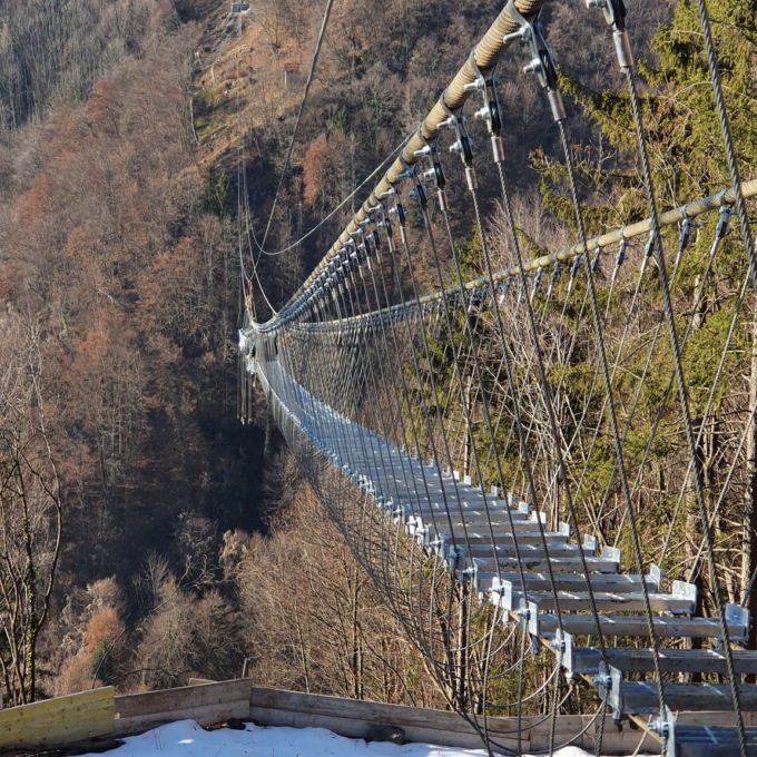 Dossena, si tirano i cavi e si poggiano le pedate del ponte tibetano sospeso sulla cava
