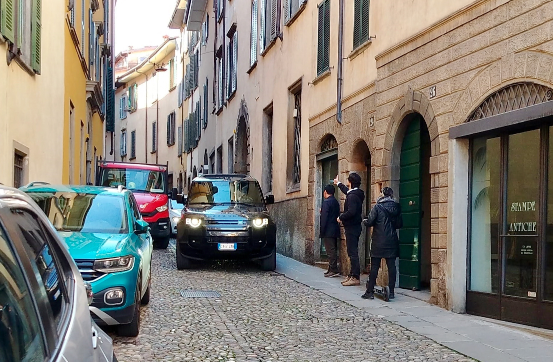 Via San Tomaso a Bergamo, le auto sui marciapiedi in una strada stretta: pedoni a rischio
